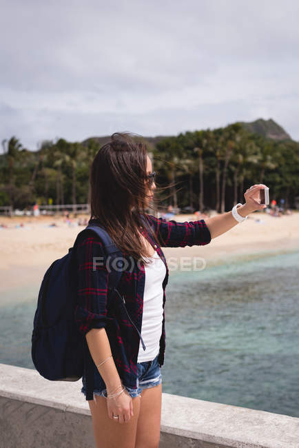 Mujer tomando selfie con teléfono móvil cerca de la playa - foto de stock