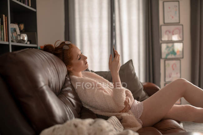 Bella donna che utilizza il telefono cellulare a casa — Foto stock