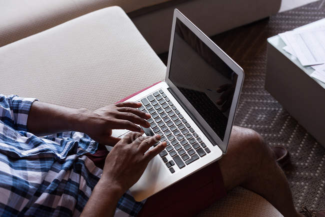 Старший чоловік сидить на дивані, використовуючи ноутбук вдома — стокове фото