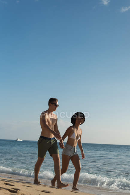Coppia che cammina insieme mano nella mano sulla spiaggia — Foto stock