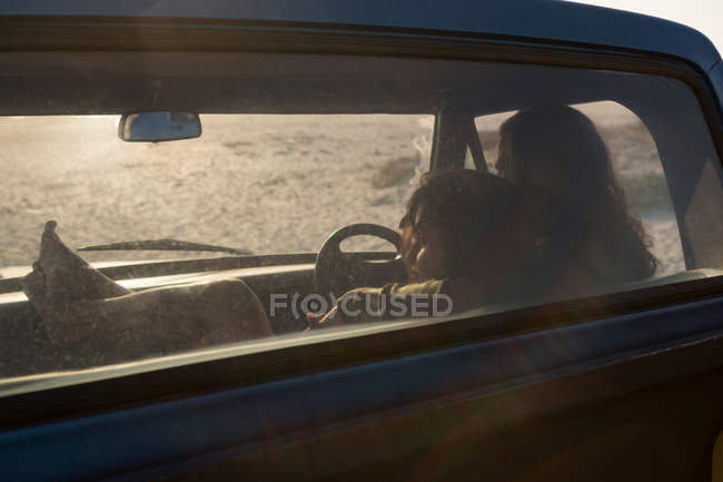 Couple se détendre dans une camionnette à la plage par une journée ensoleillée — Photo de stock