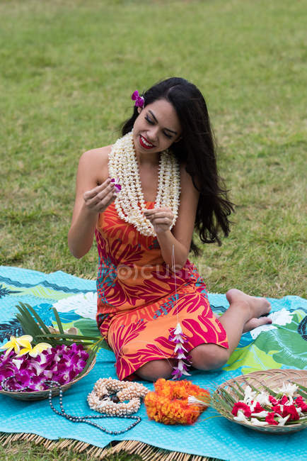 Beautiful woman preparing lei garland in the garden — Stock Photo
