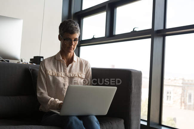 Зріла бізнес-леді використовує ноутбук в офісі — стокове фото