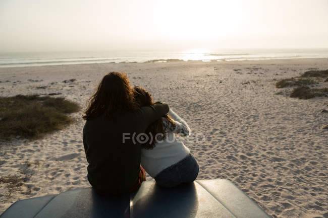 Vue arrière du couple relaxant sur le capot de la camionnette sur la plage — Photo de stock