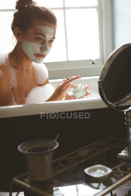 Frau cremt sich mit Feuchtigkeitscreme ein, während sie zu Hause im Badezimmer badet — Stockfoto