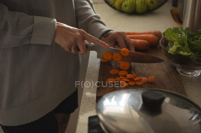 Sezione media di donna che taglia verdure in cucina — Foto stock