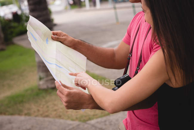 Mid section of couple looking at map in city street — Stock Photo
