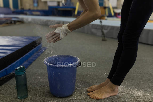 Deportiva espolvoreándose las manos con tiza en polvo en el gimnasio - foto de stock