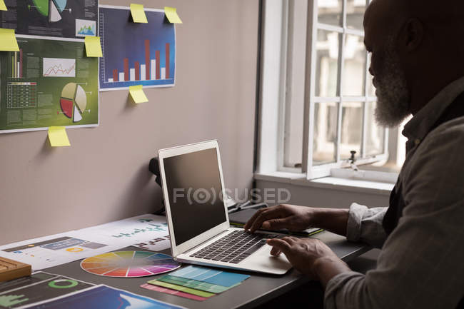 Designer gráfico sênior usando laptop na mesa no escritório — Fotografia de Stock