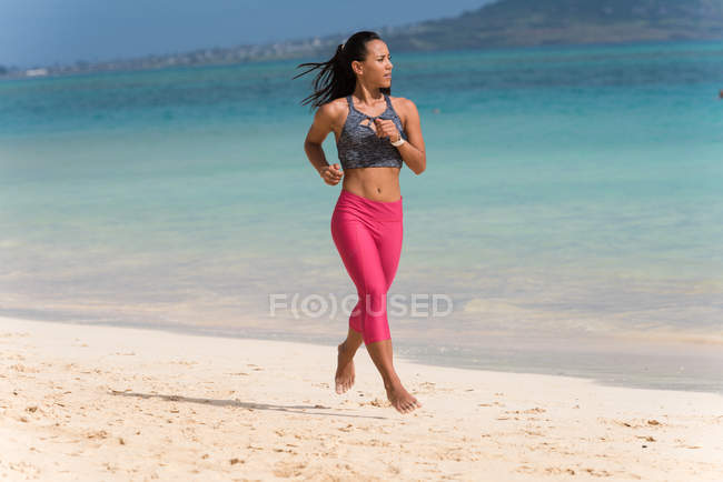 Mulher correndo na praia em um dia ensolarado — Fotografia de Stock