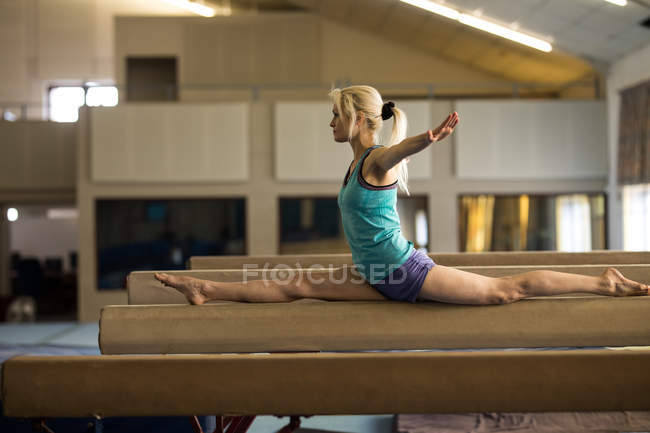 Equilibrio atlético femenino en la barra de madera en el gimnasio - foto de stock