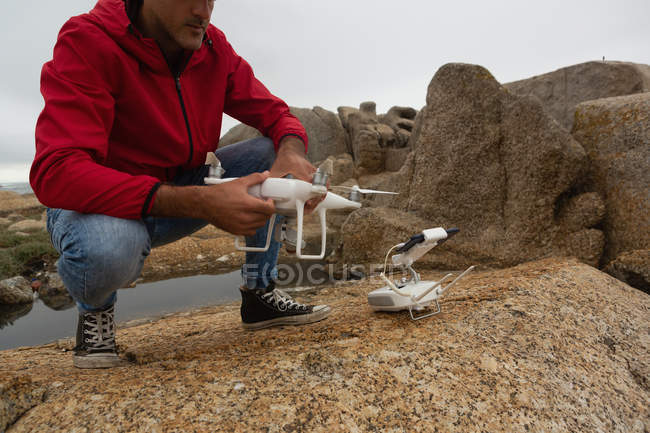Homem operando um drone voador em uma rocha — Fotografia de Stock