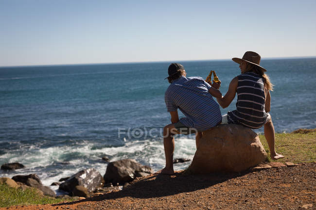 Visão traseira de amigos do sexo masculino tomando cerveja na praia — Fotografia de Stock