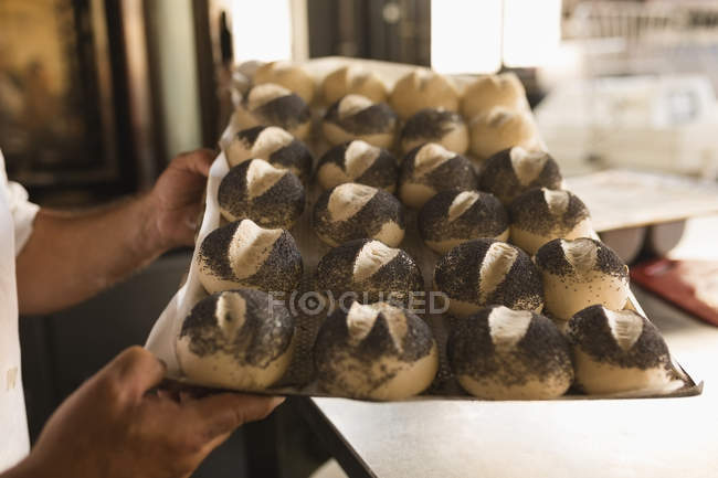Close-up of male baker holding tray of round croissants — Stock Photo