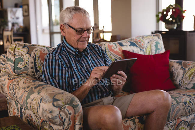 Hombre mayor usando tableta digital en la cocina en casa - foto de stock