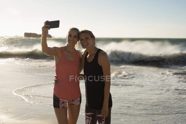 Jogadoras de voleibol do sexo feminino tirando selfie com telefone celular na praia — Fotografia de Stock