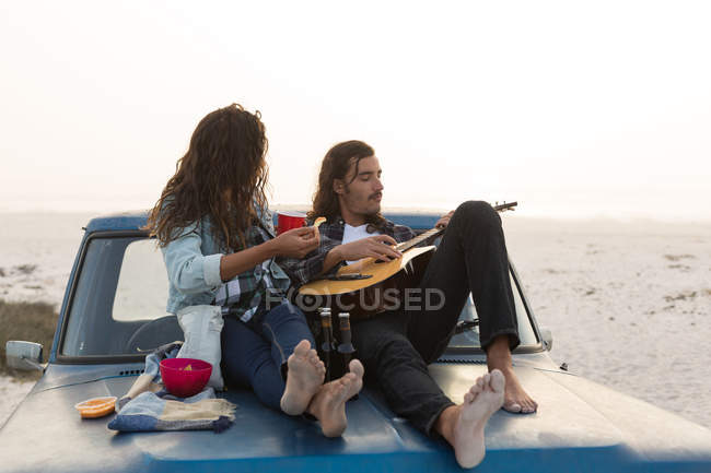 Пара веселится на капоте пикапа на пляже — стоковое фото