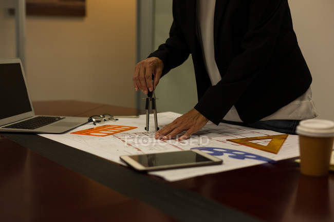 Mittelteil der Geschäftsfrau macht Blaupause im Büro — Stockfoto