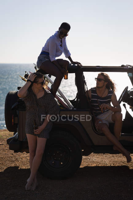 Группа друзей, взаимодействующих друг с другом на пляже в солнечный день — стоковое фото