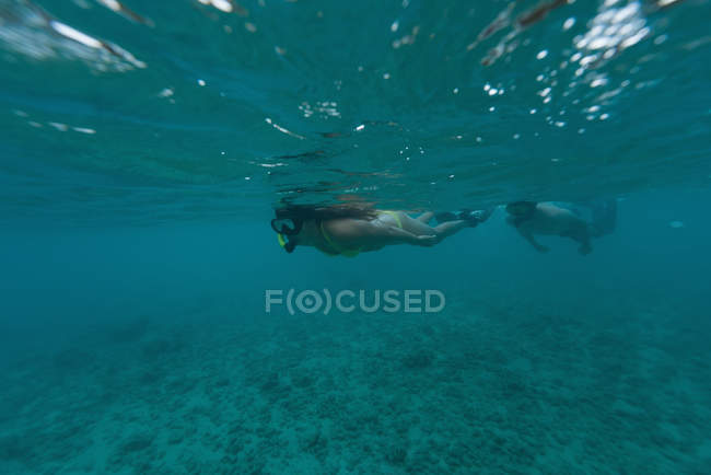 Couple scuba diving underwater in turquoise sea — Stock Photo