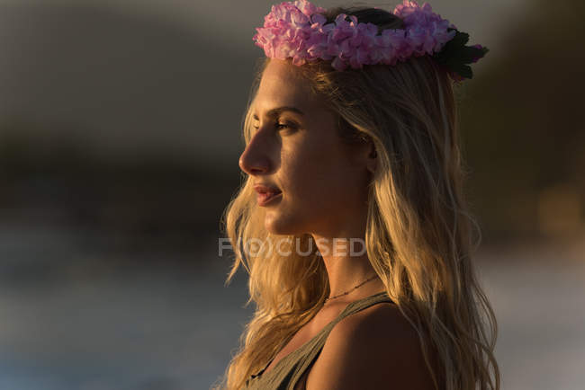 Mulher cuidadosa em coroa de flores em pé na praia — Fotografia de Stock