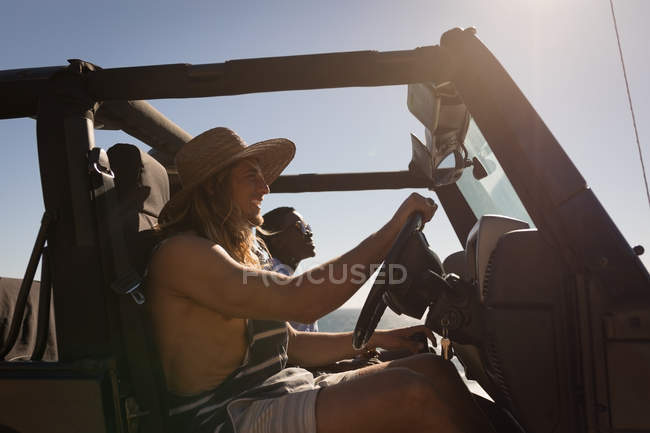 Des amis conduisent une jeep sur la plage par une journée ensoleillée — Photo de stock