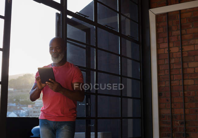 Uomo anziano attivo utilizzando tablet digitale a casa — Foto stock