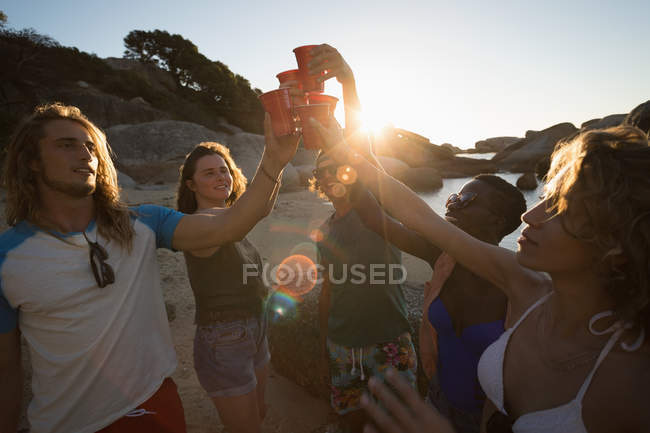 Gruppo di amici che si divertono in spiaggia al tramonto — Foto stock