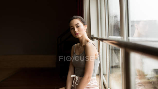 Bailarina femenina pensativa mirando por la ventana en el estudio de danza - foto de stock