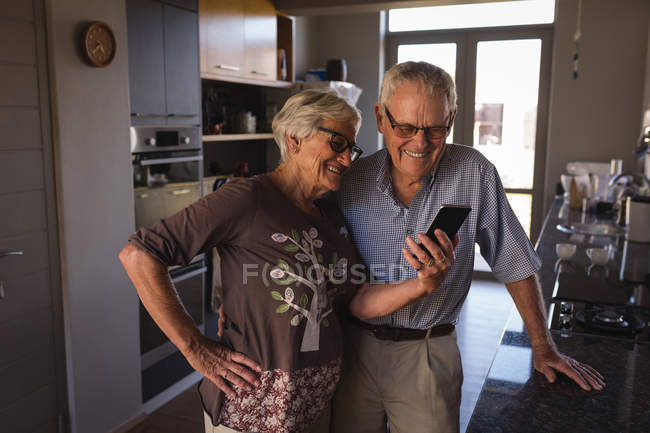 Casal de idosos chamada de vídeo no telefone celular na cozinha em casa — Fotografia de Stock