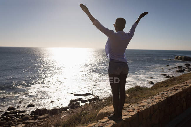 Woman standing with arms outstretched in the beach on a sunny day — Stock Photo