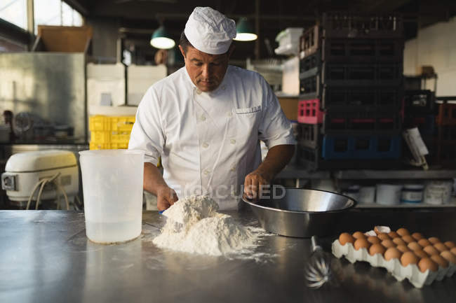 Зрелый мужчина-пекарь готовит тесто в пекарне — стоковое фото