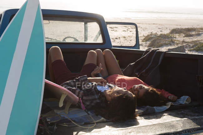 Casal relaxante em um caminhão de coleta na praia em um dia ensolarado — Fotografia de Stock