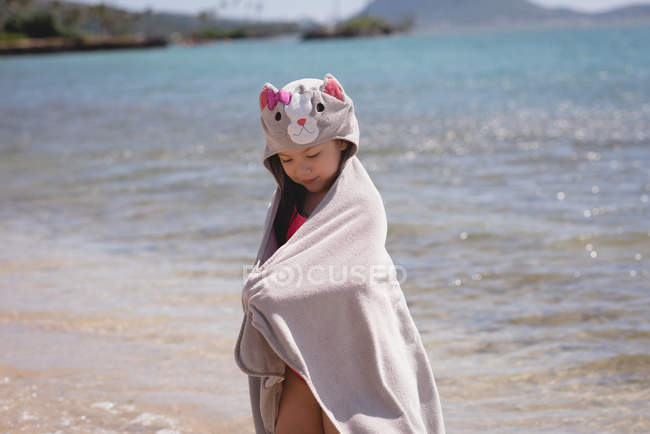Mädchen steht mit Handtuch am Strand an einem sonnigen Tag — Stockfoto
