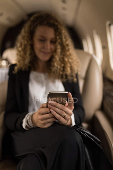Hermosa mujer de negocios utilizando el teléfono móvil en jet privado - foto de stock