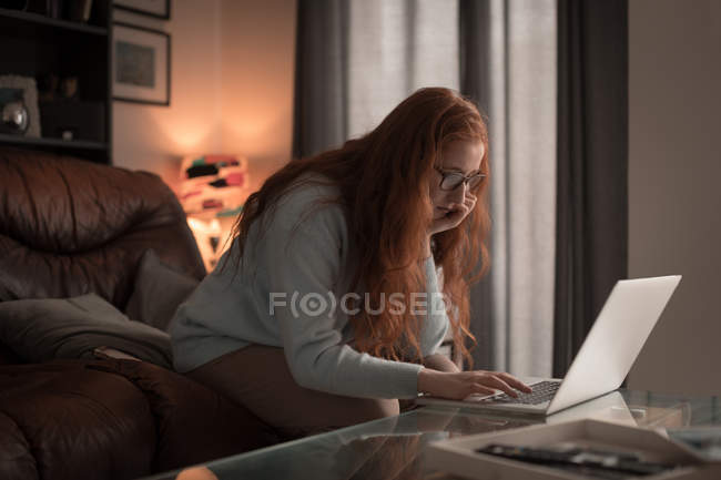 Femme utilisant un ordinateur portable dans le salon à la maison — Photo de stock