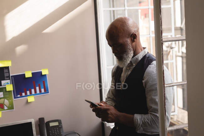 Senior graphic designer using mobile phone in office — Stock Photo