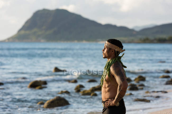 Thoughtful male fire dancer standing with hands on hip at beach — Stock Photo