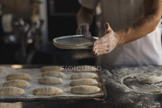 Средняя секция пекаря мужского пола готовит тесто в пекарне — стоковое фото