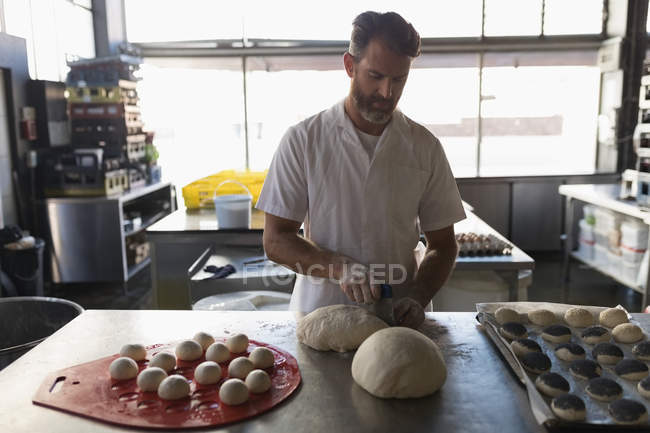 Mature male baker preparing dough in bakery shop — Stock Photo