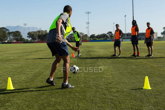 Jogadores praticando futebol no campo em um dia ensolarado — Fotografia de Stock