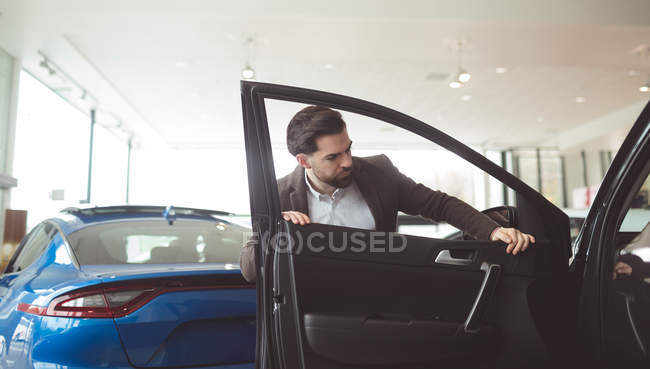 Bonito vendedor examinando carro no showroom — Fotografia de Stock