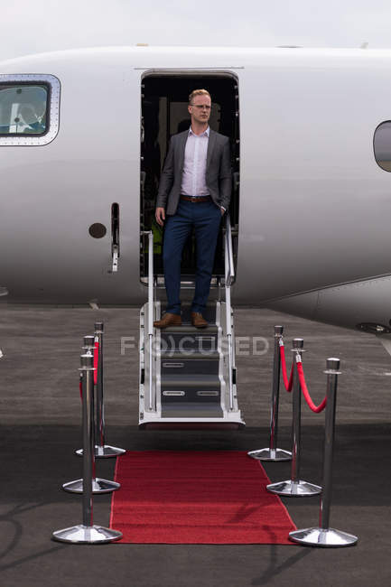Businessman standing at the entrance of private jet at terminal — Stock Photo