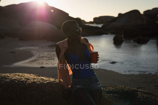 Femme prenant un verre à la plage au crépuscule — Photo de stock