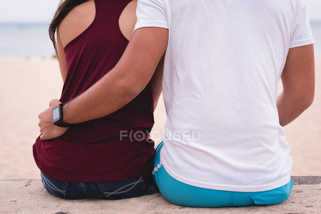 Vue arrière du couple assis ensemble sur la plage — Photo de stock