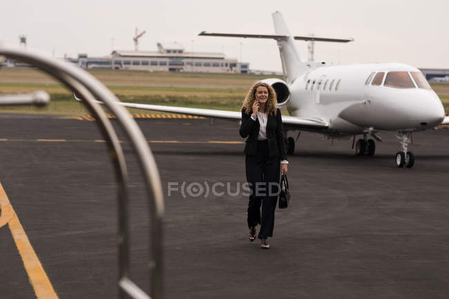 Schöne Geschäftsfrau telefoniert beim Gehen am Terminal — Stockfoto