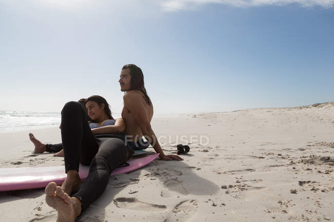 Coppia di surfisti che si rilassa in spiaggia in una giornata di sole — Foto stock