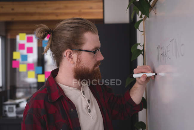 Male executive writing on whiteboard in office — Stock Photo