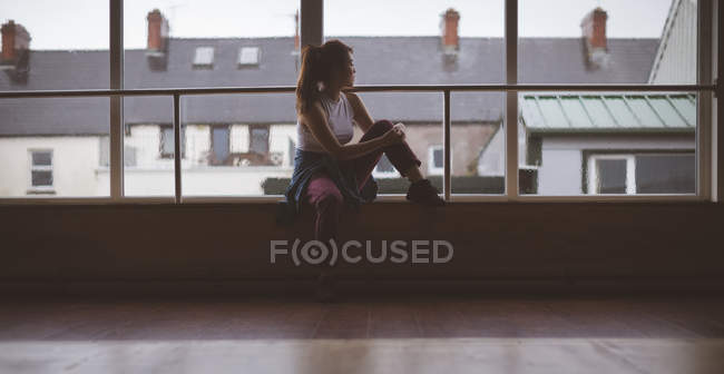 Задумчивая танцовщица смотрит в окно в танцевальной студии — стоковое фото