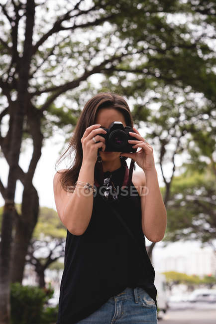 Femme cliquetant photo avec appareil photo numérique dans la ville — Photo de stock
